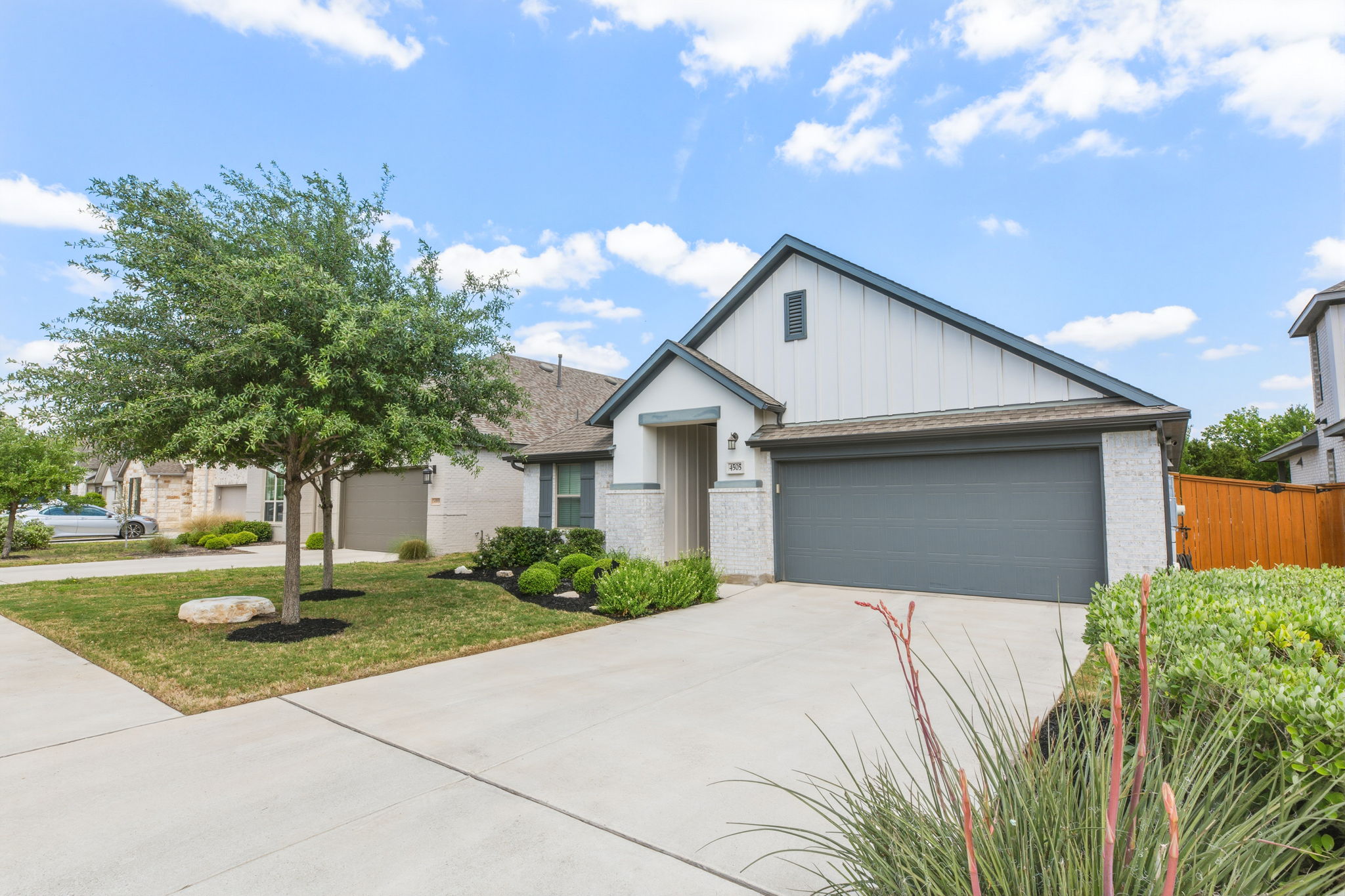 4505 Post Loop Round Rock, TX 78681 - Photo 3 of 40 View of front of property featuring board and batten siding, brick siding, concrete driveway, an attached garage, and a front yard