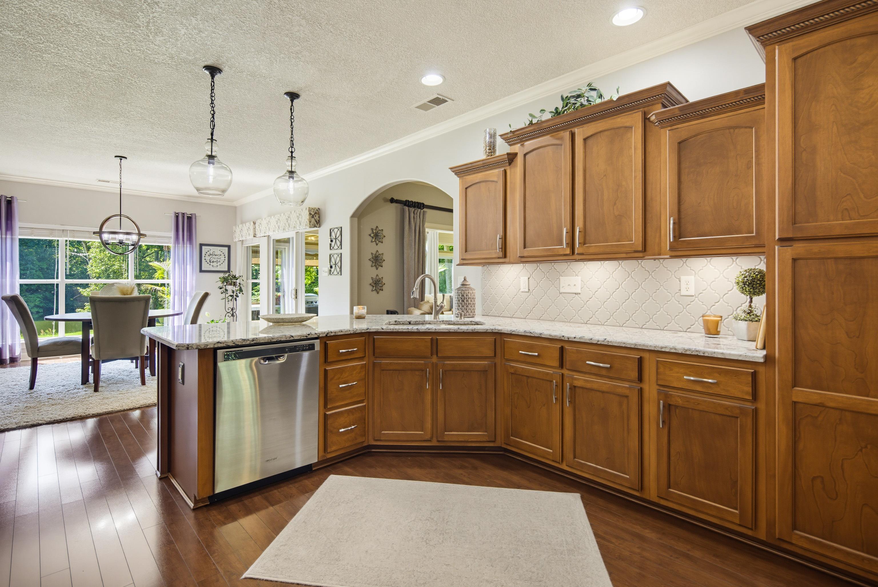 243 Hayes Road Munford, TN 38058 - Photo 10 of 25 Gourmet kitchen featuring wood-finish flooring, custom cabinetry, stainless steel appliances, granite countertops, and a full tile backsplash