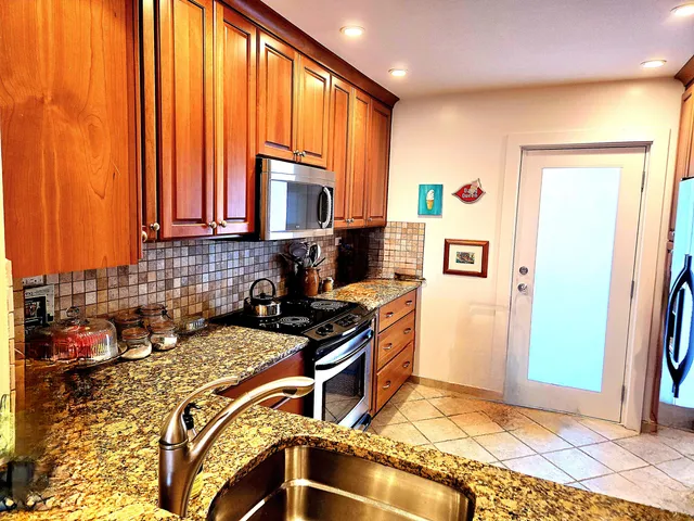 a kitchen with stainless steel appliances granite countertop a refrigerator and a stove top oven