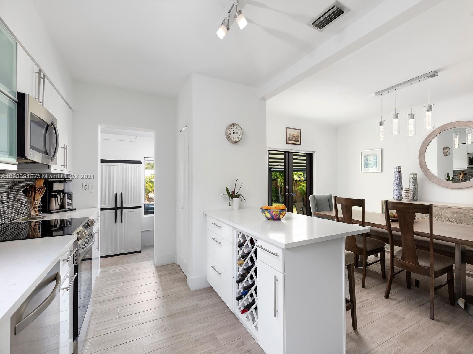 457 Southwest 27th Road Miami, FL 33129 - Photo 8 of 20 a large kitchen with kitchen island a stove a sink a dining table and chairs