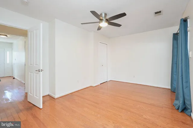 an empty room with wooden floor and a ceiling fan