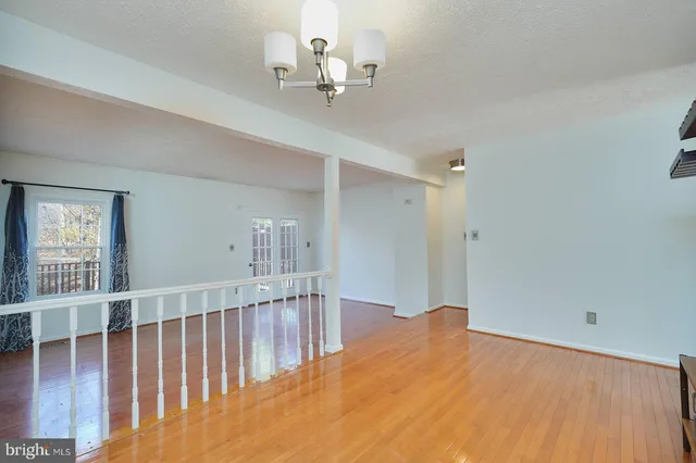 a view of a hallway with wooden floor and chandelier