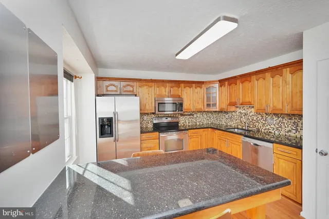 a kitchen with stainless steel appliances granite countertop a refrigerator and a sink