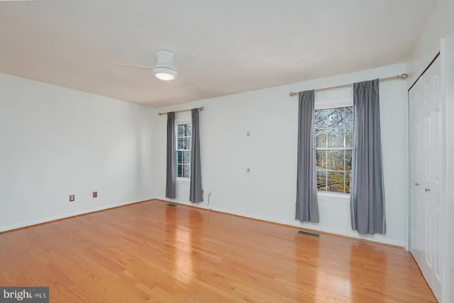 a view of empty room with wooden floor and fan