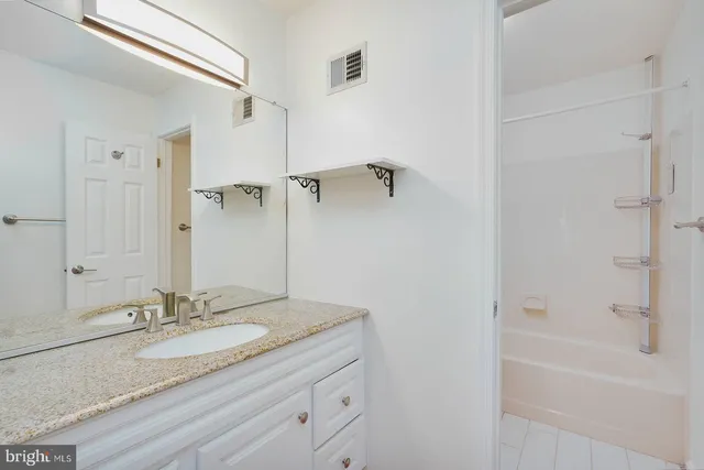 a bathroom with a granite countertop sink a mirror and a bathtub