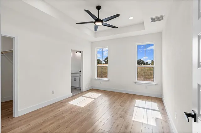 a view of an empty room with window and wooden floor