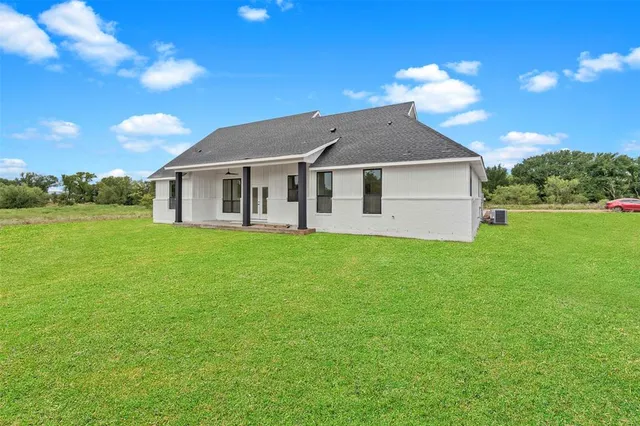 a view of a house next to a big yard and large trees