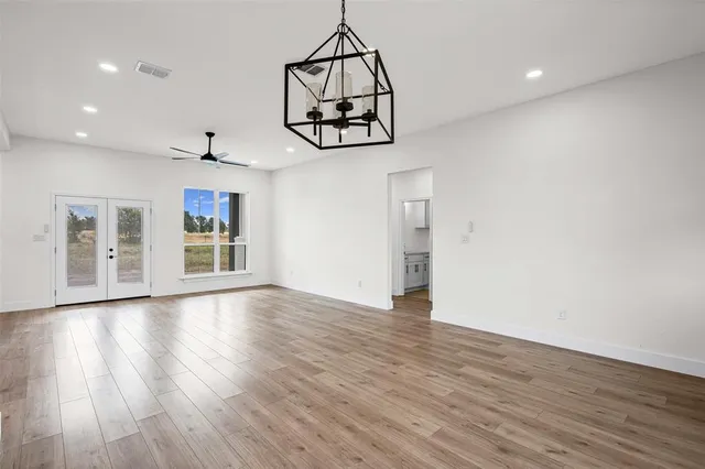 a view of an empty room with wooden floor and windows