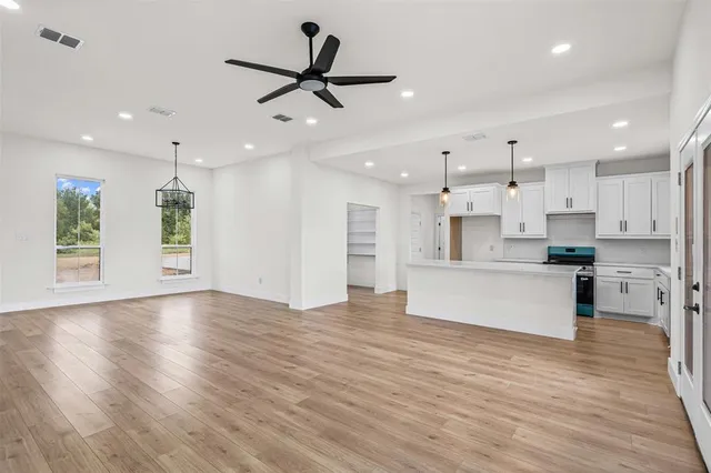 a view of kitchen with kitchen island wooden floors appliances and cabinets