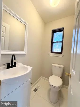 a bathroom with a toilet a sink a mirror and a window