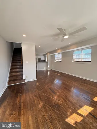 a view of an empty room with wooden floor and stairs
