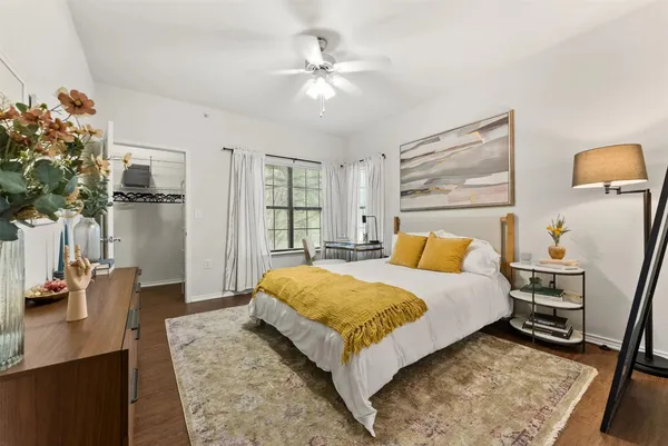 a spacious bedroom with a bed a dresser and potted plant