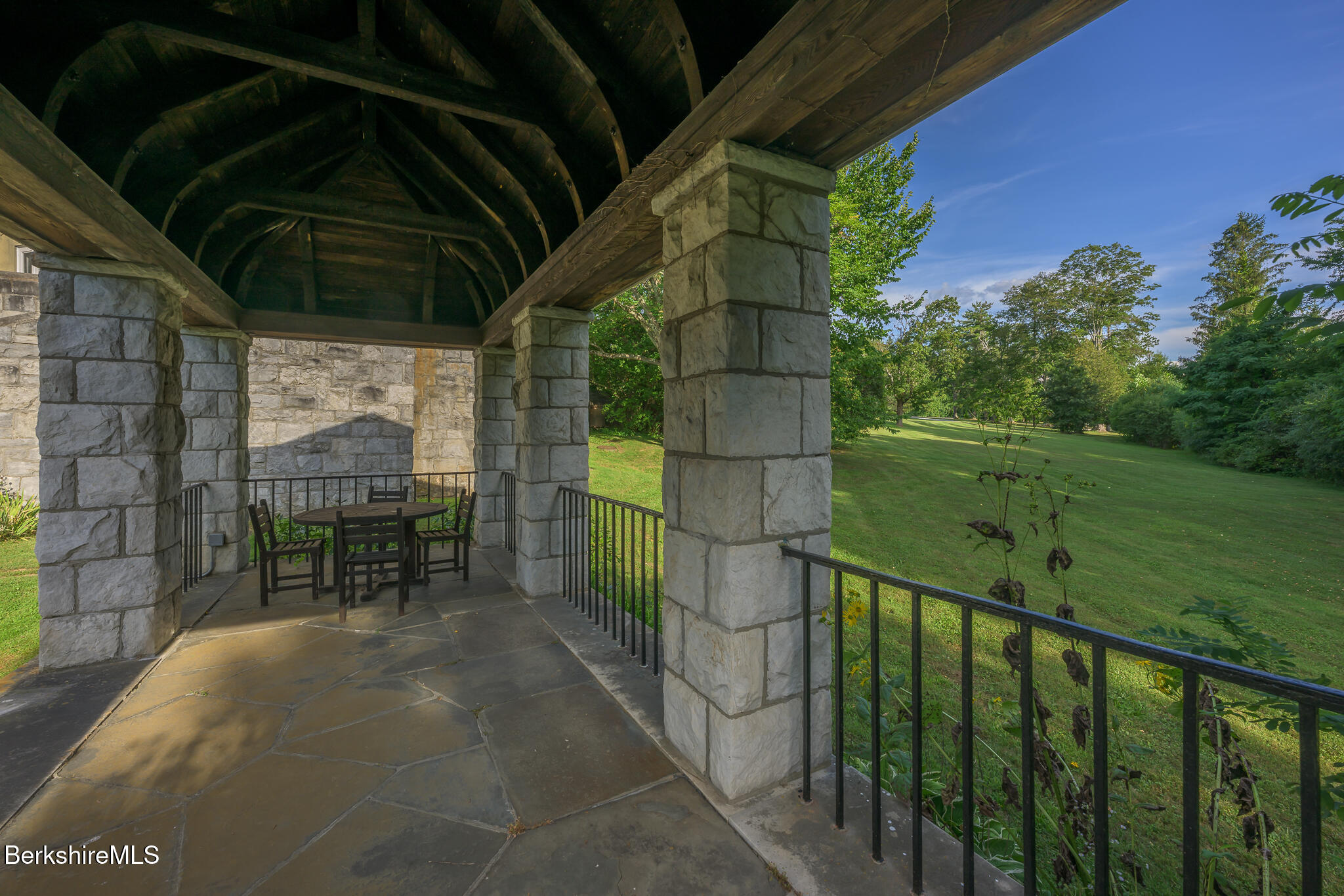 11 Prospect Hill Road, Unit F Stockbridge, MA 01262 - Photo 45 of 51 a view of a porch with a table and chair under an umbrella
