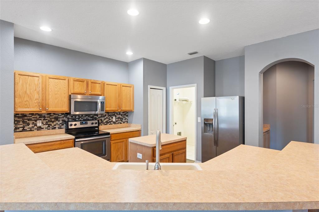 14027 Bensbrook Drive Spring Hill, FL 34609 - Photo 14 of 61 a kitchen with stainless steel appliances kitchen island granite countertop a refrigerator oven a sink dishwasher with a dining table and chairs