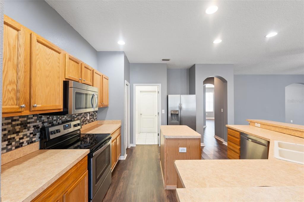 14027 Bensbrook Drive Spring Hill, FL 34609 - Photo 15 of 61 a large kitchen with stainless steel appliances a stove a sink dishwasher and wooden cabinets with wooden floor