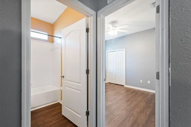 an empty room with wooden floor and ceiling fan