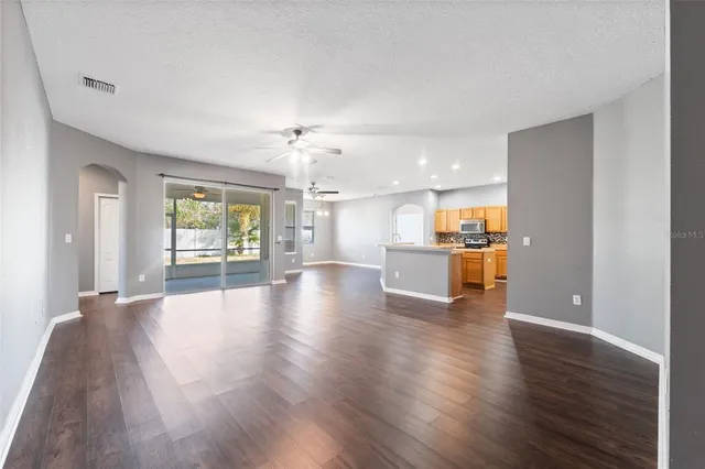 a view of a kitchen and an empty room with wooden floor