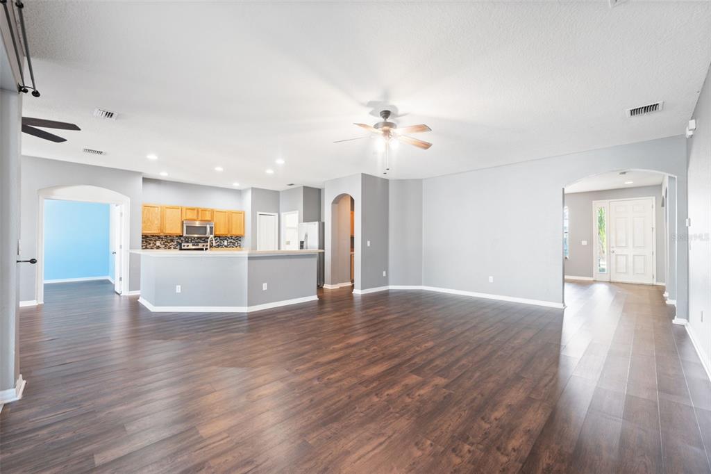 14027 Bensbrook Drive Spring Hill, FL 34609 - Photo 9 of 61 a view of an empty room with wooden floor and a kitchen