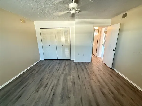 a view of a room with wooden floor a ceiling fan