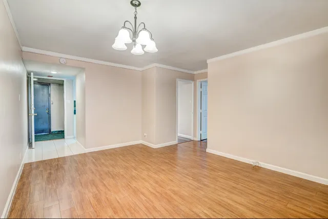 a view of an empty room with wooden floor and chandelier