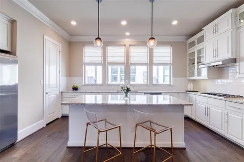 a kitchen with stainless steel appliances granite countertop a stove a sink a center island a refrigerator and wooden floor