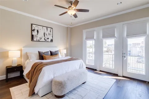 a spacious bedroom with a bed painting on wall and a large window