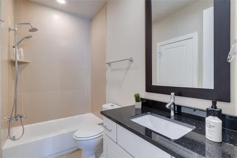 a bathroom with a granite countertop sink a toilet a mirror and shower