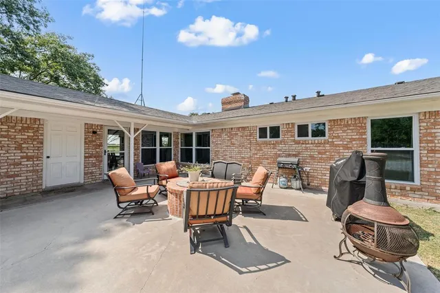 a view of a house with a barbeque and large trees