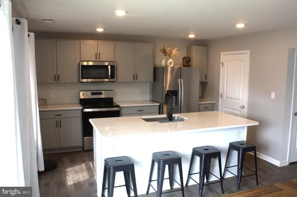 a kitchen with stainless steel appliances a table chairs and a refrigerator