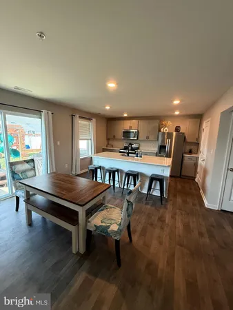 a kitchen with stainless steel appliances granite countertop a dining table chairs refrigerator and microwave