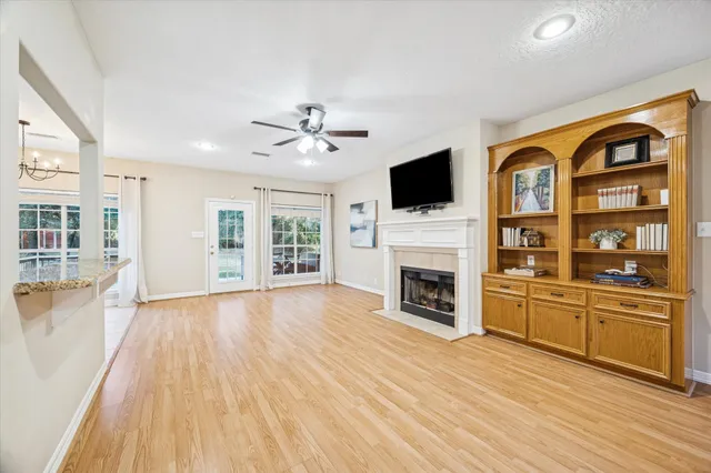 a view of a livingroom with a fireplace a flat screen tv and windows
