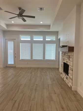 a view of empty room with wooden floor fireplace and a window