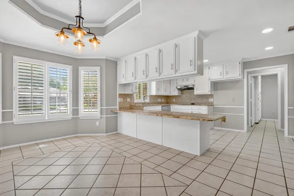 a open kitchen with kitchen island granite countertop a sink window and white cabinets