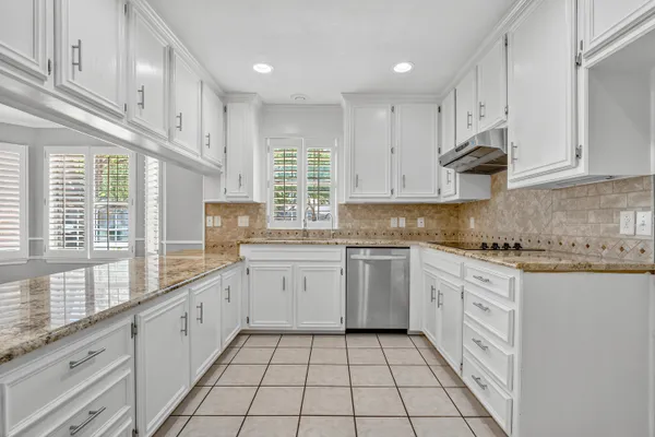 a kitchen with granite countertop white cabinets stainless steel appliances a sink and a window