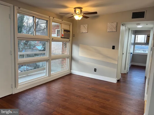 a view of an empty room with wooden floor and a window
