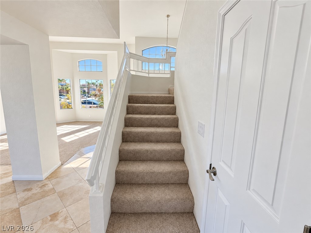 43 Bayridge Road Henderson, NV 89074 - Photo 30 of 47 A carpeted staircase ascends near tiled flooring and light-filled architectural spaces.