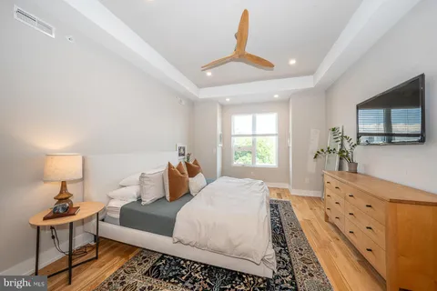 a bedroom with a bed a window and potted plant on dresser