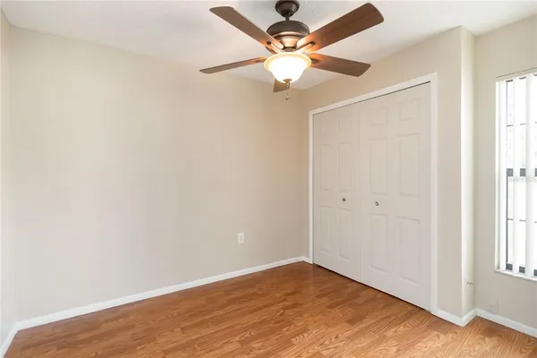 an empty room with wooden floor fan and windows