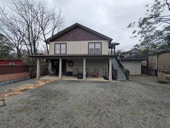 a view of a house with a yard and large tree