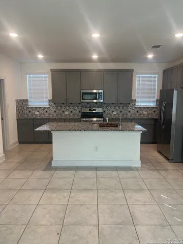 a large kitchen with granite countertop a stove a sink a microwave and a refrigerator