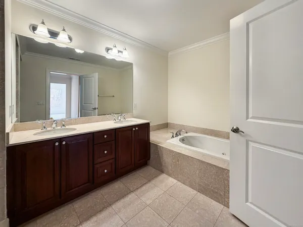 a spacious bathroom with a tub double sink and mirror