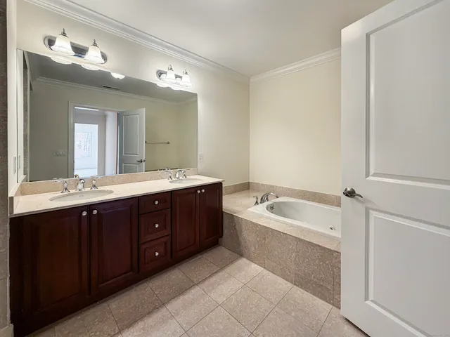 a spacious bathroom with a tub double sink and mirror