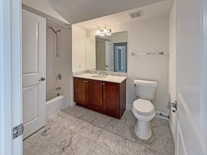 a bathroom with a toilet sink vanity granite and shower