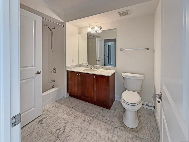 a bathroom with a toilet sink vanity granite and shower