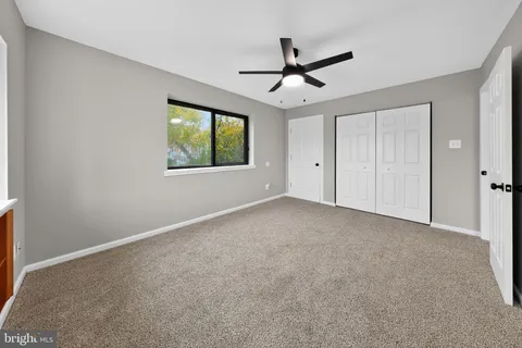 a view of a big room with a ceiling fan and windows