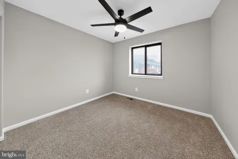an empty room with a window and a ceiling fan