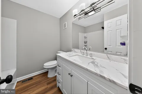 a bathroom with a granite countertop sink a toilet and a mirror