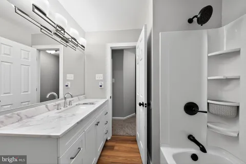 a spacious bathroom with a granite countertop sink a mirror and shower
