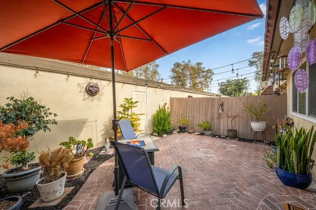 a backyard of a house with table and chairs under an umbrella