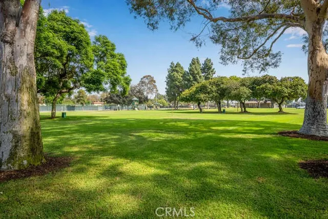 a view of grassy field with benches and trees all around